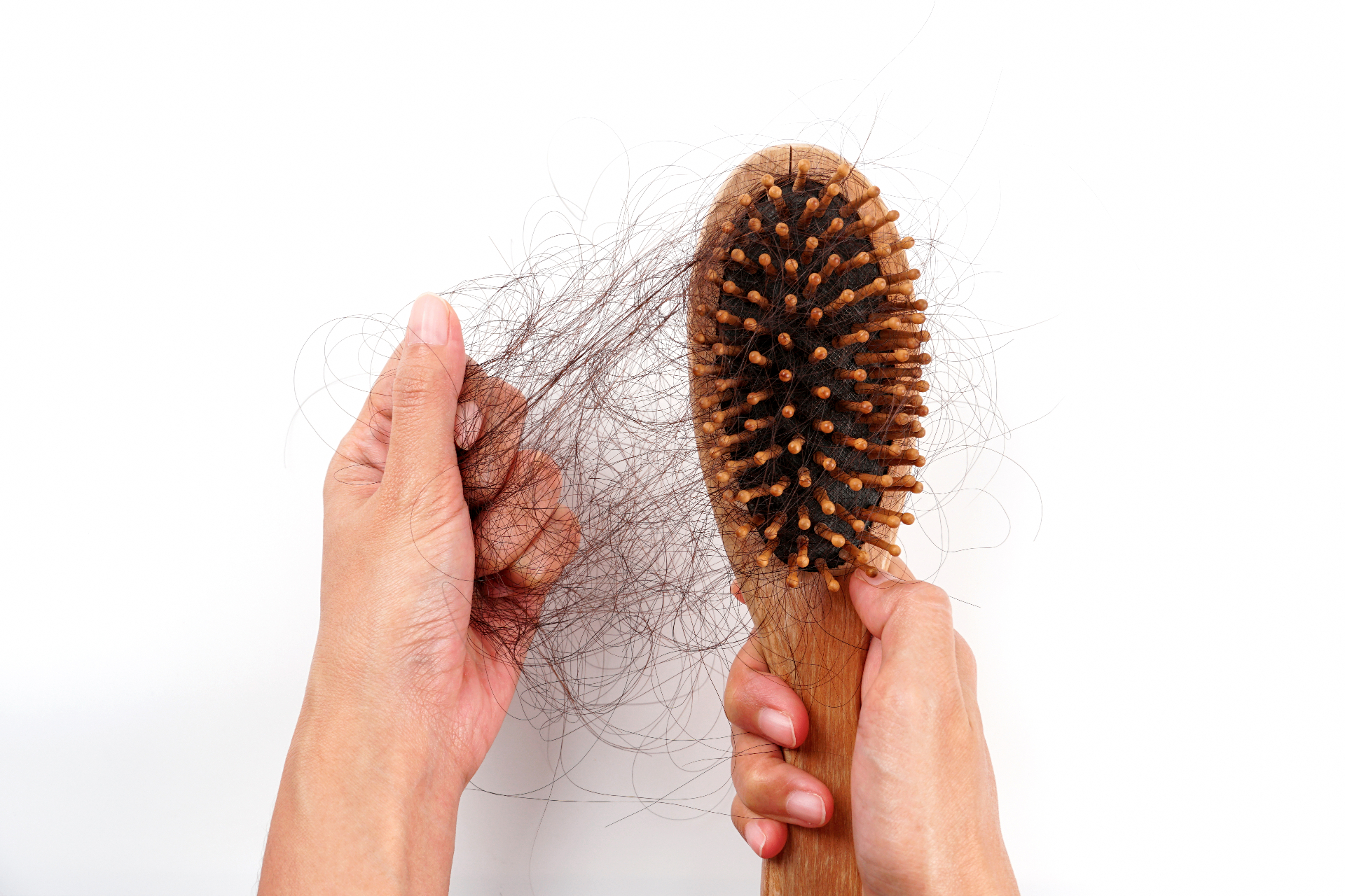 Mãos retirando tufo de cabelo da escova